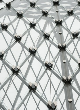 Detalle de una estructura de vidrio con patrones geométricos y uniones metálicas.